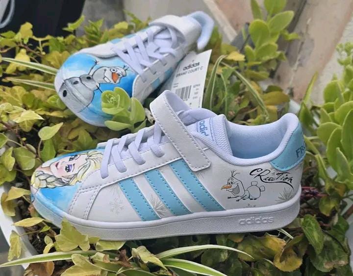 ❄️ Scarpe Adidas Dipinte a Mano – Tema Frozen 👟🎨 Porta la magia di Arendelle ai tuoi piedi con queste scarpe Adidas personalizzate a mano ispirate a Frozen, il celebre cartone Disney! Un paio unico ed esclusivo, realizzato con passione e materiali di alta qualità, ideale per chi ama Elsa, Anna e l’incanto dell’inverno! 💙✨ 🧩 *Coordinabile su richiesta:* È possibile ordinare *un portafoglio , una borsa o un giacchetto perfettamente abbinato* con lo stesso stile e soggetto ! 🖌️ Dettagli del prodotto: - Sc