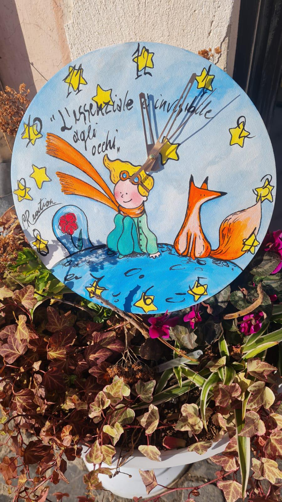 Orologio da Parete Dipinto a Mano - Il Piccolo Principe - Accessorio Unico e Magico per la Tua Casa Descrizione: Aggiungi un tocco di poesia e magia alla tua casa con questo orologio da parete dipinto a mano, ispirato al celebre Piccolo Principe. Ogni dettaglio di questo orologio è realizzato con cura per catturare l’essenza senza tempo di questa storia, trasformando un semplice oggetto quotidiano in una vera e propria opera d’arte.