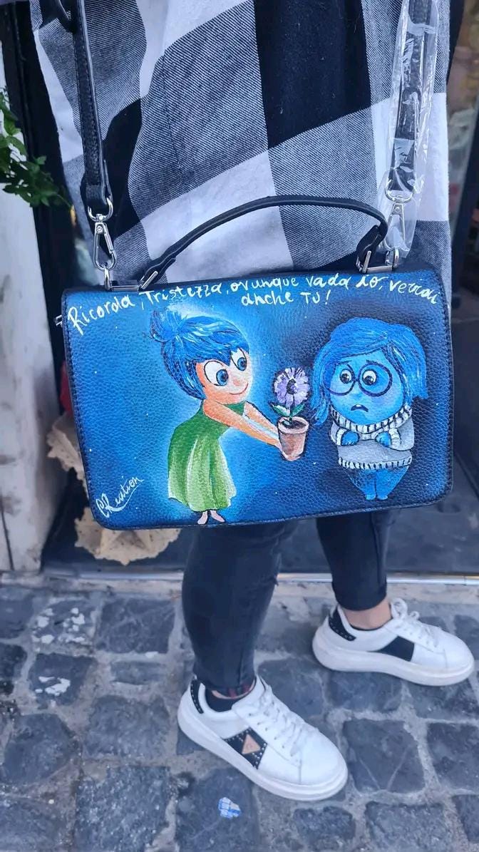 Borsa Dipinta a Mano - Inside Out | Pezzo Unico Artigianale ✨ Un accessorio magico per gli amanti della creatività e delle emozioni! ✨ Questa borsa unica è interamente dipinta a mano con colori acrilici resistenti e raffigura i simpatici e amati personaggi di Inside Out! Perfetta per chi ama il mondo Disney-Pixar e vuole portare sempre con sé un tocco di fantasia e colore.