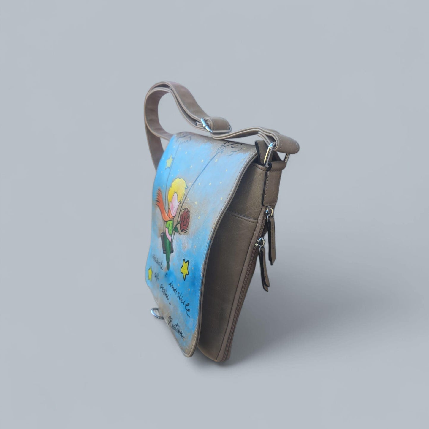 Borsa dipinta a mano – Il Piccolo Principe con frase iconica – Pelle/Ecopelle di alta qualità *Descrizione:* Lasciati ispirare dalla magia senza tempo de *Il Piccolo Principe* con questa borsa capiente, dipinta interamente a mano. Il soggetto principale è l’iconico protagonista del celebre racconto, accompagnato da una frase simbolica che emoziona grandi e piccini. Ogni borsa è realizzata su *pelle o ecopelle di alta qualità*, resistente e piacevole al tatto, e dipinta con *colori acrilici professionali* ad