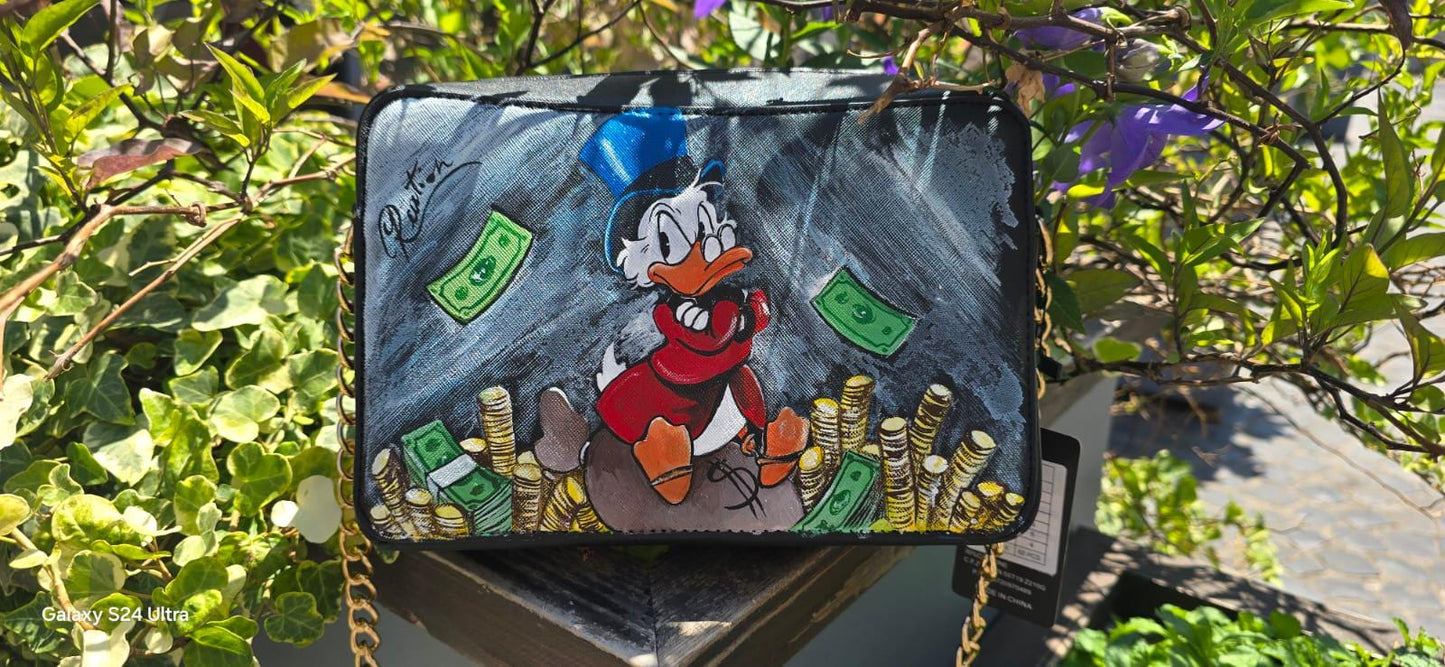 *Borsa Dipinta a Mano – Zio Paperone 💰🦆* Un omaggio al personaggio più iconico e ricco del mondo Disney: *Zio Paperone*! Questa *borsa in ecopelle dipinta a mano* raffigura il celebre papero con il suo immancabile cilindro e le monete d'oro, simbolo di ingegno e determinazione. Ogni dettaglio è realizzato a mano con cura artigianale e *colori acrilici professionali*, rendendo ogni pezzo unico.