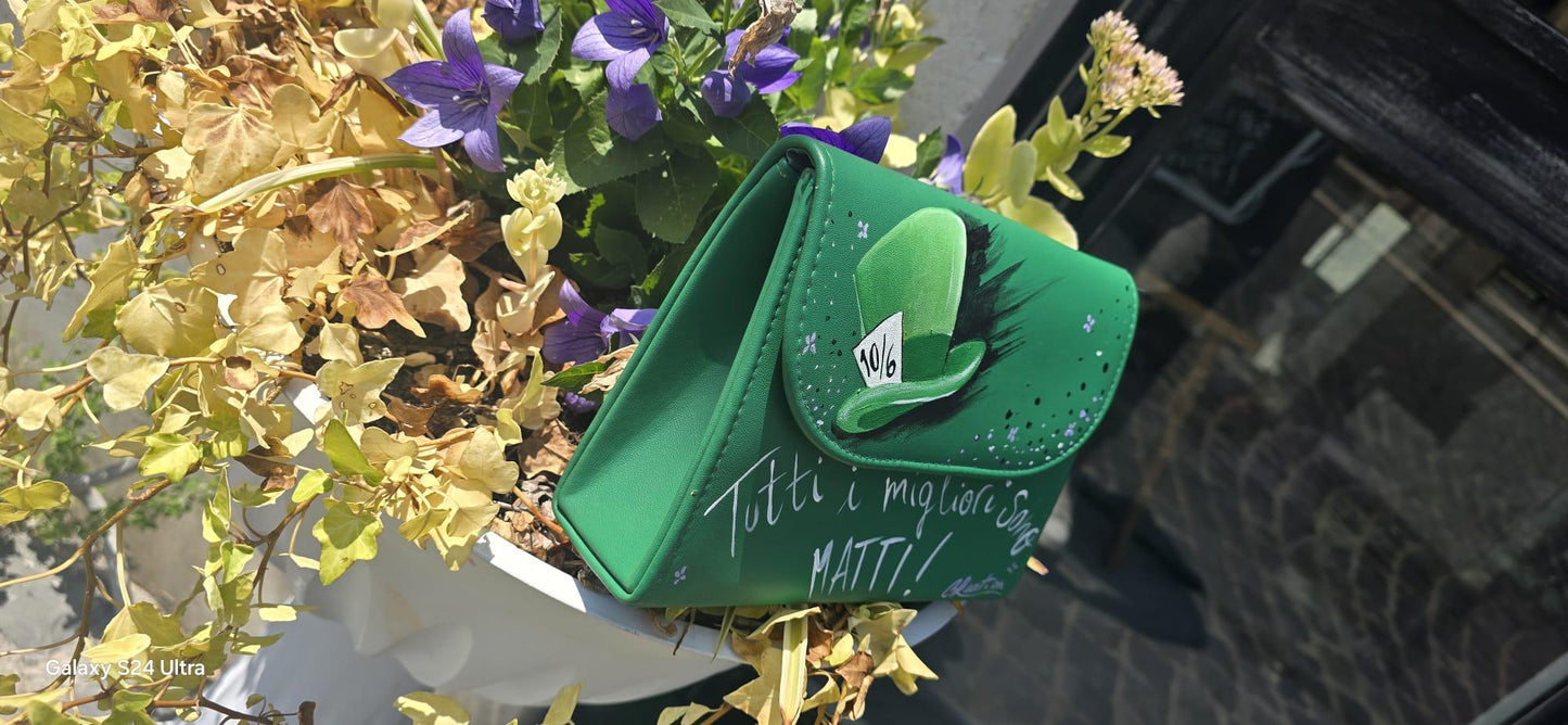 *Borsa Dipinta a Mano – Cappellaio Matto 🎩✨* Un pezzo unico e originale per chi ama il mondo incantato di Alice nel Paese delle Meraviglie! Questa borsa in ecopelle è interamente *dipinta a mano* con colori acrilici professionali e sigillata per durare nel tempo. Il *soggetto principale* è l’iconico *cappello del Cappellaio Matto*, accompagnato dalla celebre frase: *“Tutti i migliori sono matti”*
