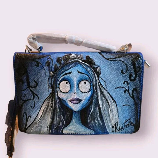 *Borsa Dipinta a Mano – Sposa Cadavere 💀🌹* Porta con te un po' di *magia gotica* e *romanticismo oscuro* con questa *borsa dipinta a mano* ispirata alla celebre *Sposa Cadavere*! 🎨✨ Ogni borsa è realizzata con *colori acrilici di alta qualità* su *ecopelle resistente*, immortalando la figura di Emily in tutto il suo misterioso fascino. Perfetta per gli amanti del *film di Tim Burton*, questa borsa unisce arte e stile gotico in un accessorio unico! 🖤 🧩 *Coordinabile su richiesta:* È possibile ordinare *