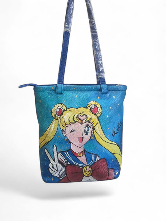 *Borsa dipinta a mano – Soggetto principale: Sailor Moon* ✨ Porta con te la magia delle stelle con questa splendida borsa dipinta a mano ispirata al mondo di *Sailor Moon*. Un accessorio unico e capiente, perfetto per chi ama l’artigianato e desidera distinguersi con stile! 🎨 Ogni borsa è un pezzo unico, realizzato interamente a mano con colori acrilici resistenti su ecopelle di alta qualità. Il soggetto principale è la mitica guerriera Sailor Moon, simbolo di forza, amicizia e femminilità.