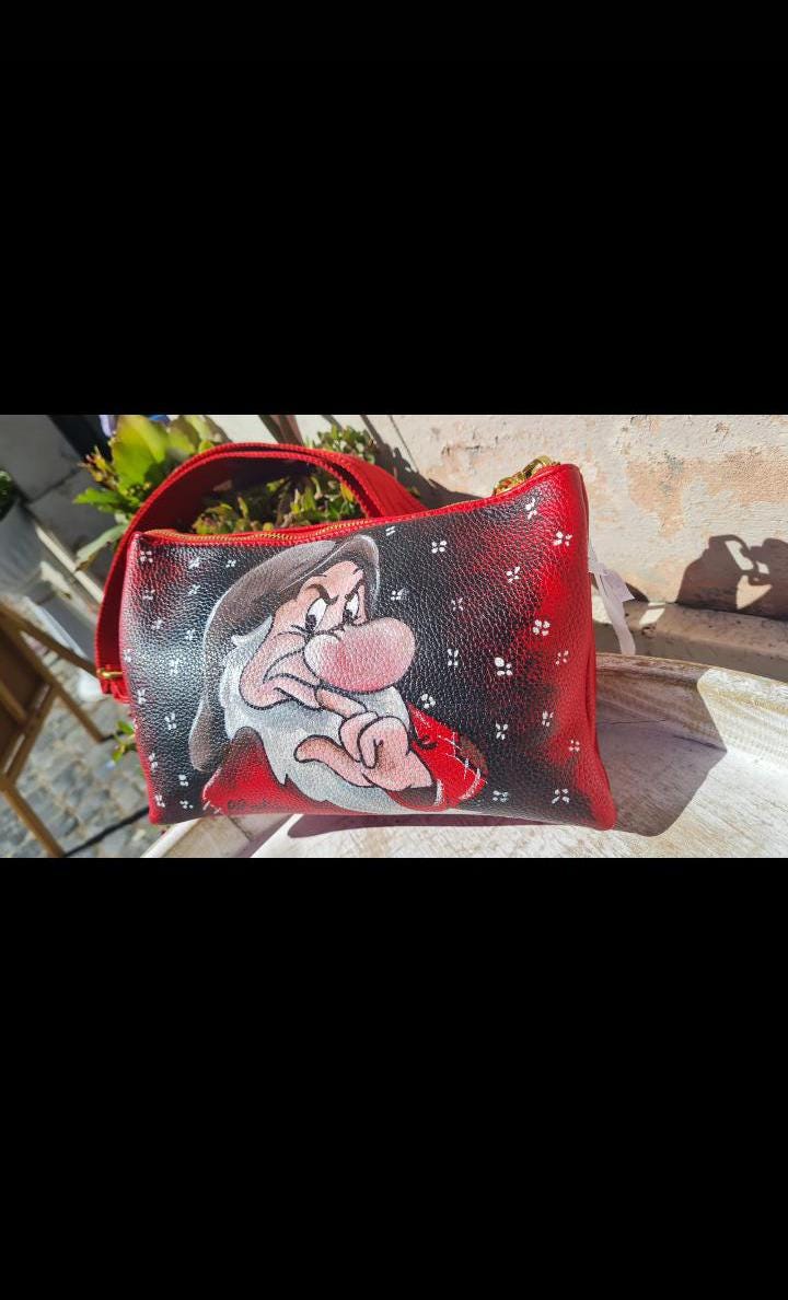 Borsa a Tracolla con Zip Dipinta a Mano - Brontolo | Biancaneve e i Sette Nani | Accessorio Unico e Originale 🧩 *Coordinabile su richiesta:* È possibile ordinare *un portafoglio o un giacchetto perfettamente abbinato* con lo stesso stile e soggetto ! Aggiungi un tocco di magia e personalità al tuo stile con questa borsa a tracolla dipinta a mano, che raffigura il caratteristico e burbero Brontolo di Biancaneve e i Sette Nani