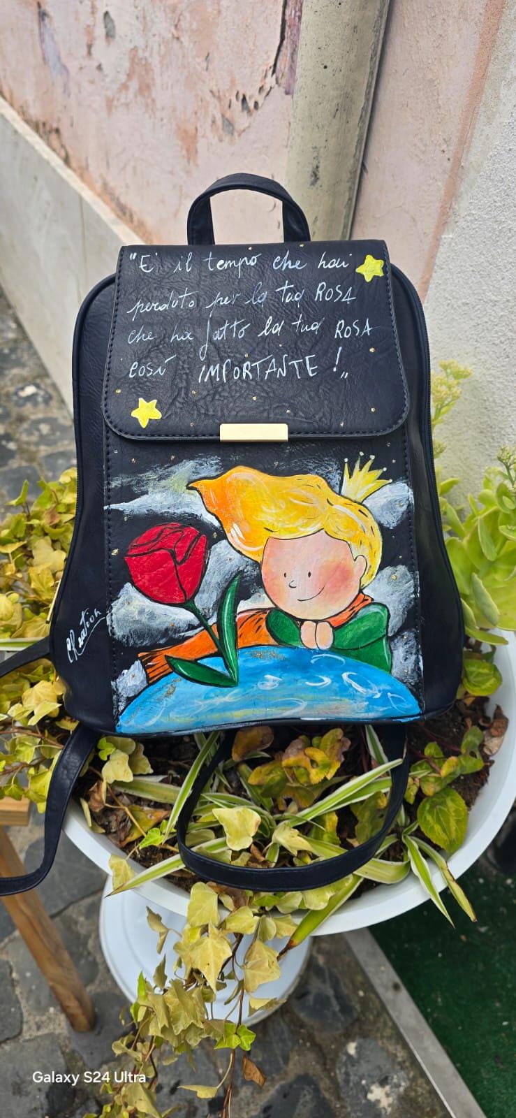 *Zaino nero dipinto a mano – Il Piccolo Principe | Citazione iconica ✨🌹* 🧩 *Coordinabile su richiesta:* È possibile ordinare *un portafoglio o un giacchetto perfettamente abbinato* con lo stesso stile e soggetto ! Zainetto in ecopelle nera con illustrazione realizzata a mano ispirata al celebre personaggio de *Il Piccolo Principe*, accanto alla sua rosa. Sul patta è riportata la frase più amata del libro