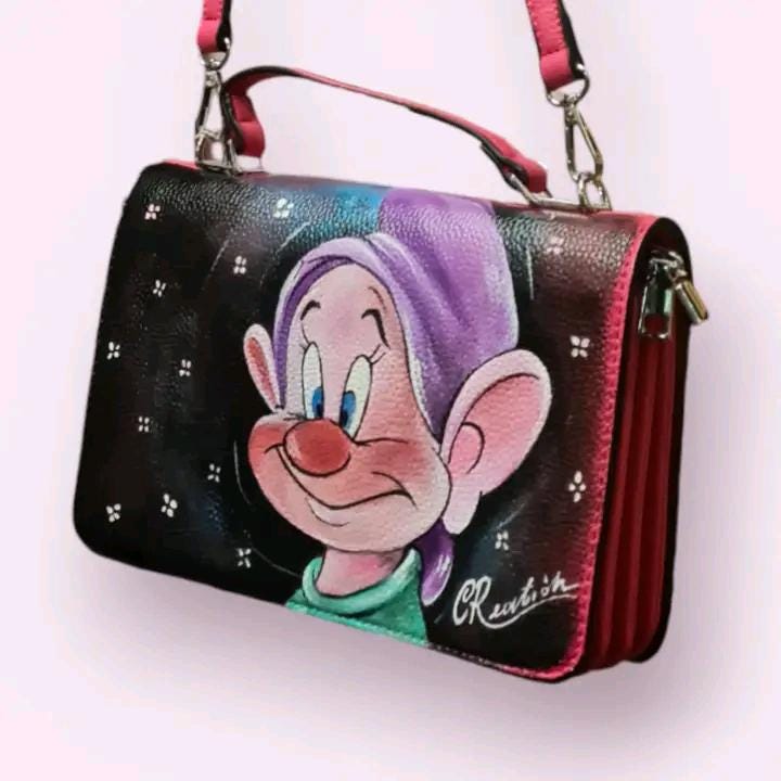 Borsa Dipinta a Mano con Cucciolo dei Sette Nani - Borsa Unica in Ecopelle, Personalizzabile, Regalo per Amanti dei Cartoni 🧩 *Coordinabile su richiesta:* È possibile ordinare *un portafoglio o un giacchetto perfettamente abbinato* con lo stesso stile e soggetto ! Descrizione: Questa borsa dipinta a mano è ispirata al simpatico cucciolo dei Sette Nani, celebre personaggio del cartone animato Biancaneve e i sette nani. Realizzata in ecopelle di alta qualità, la borsa presenta un’illustrazione unica che catt