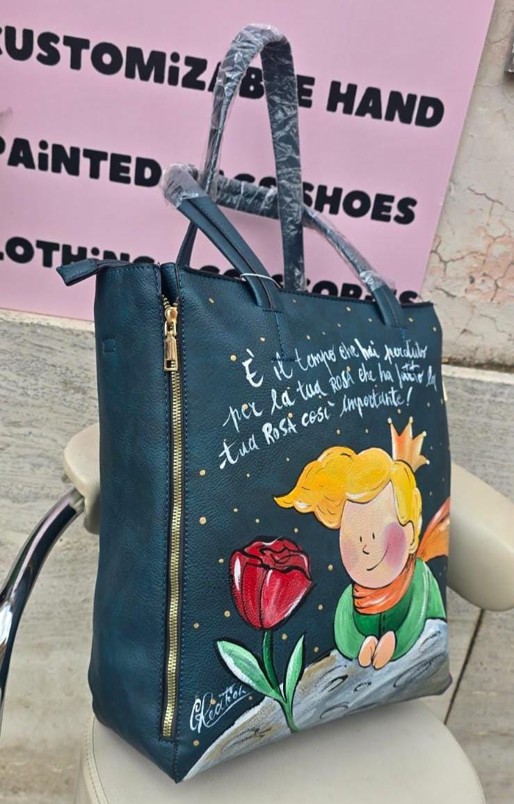 Borsa Grande in Ecopelle Dipinta a Mano – Ispirazione Il Piccolo Principe con Rosa Rosa e Frase Iconica ✨🌹 Descrizione : 🎨 Borsa artigianale grande in ecopelle/pelle, dipinta interamente a mano con amore e cura. Il soggetto principale è ispirato al poetico mondo de Il Piccolo Principe, rappresentato con una delicata rosa rosa 🌹 e una frase iconica che rende il pezzo ancora più speciale 💫. 👜 Capiente, comoda e originale