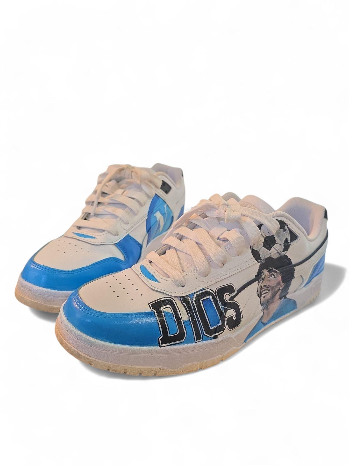Scarpe Puma dipinte a mano – Maradona &amp; Scudetto Napoli • Arte da indossare • Custom sneakers --- *Descrizione prodotto:* ⚽ *Scarpe Puma dipinte a mano – Diego Armando Maradona &amp; Scudetto Napoli* Un omaggio unico e potente al Pibe de Oro e alla grandezza del Napoli. Un'opera d’arte da indossare, creata interamente a mano con *colori acrilici professionali*, resistenti a usura e intemperie. 👟 Ogni dettaglio è curato con passione: il ritratto di *Maradona*, i colori del *Napoli* e il simbolico *scude