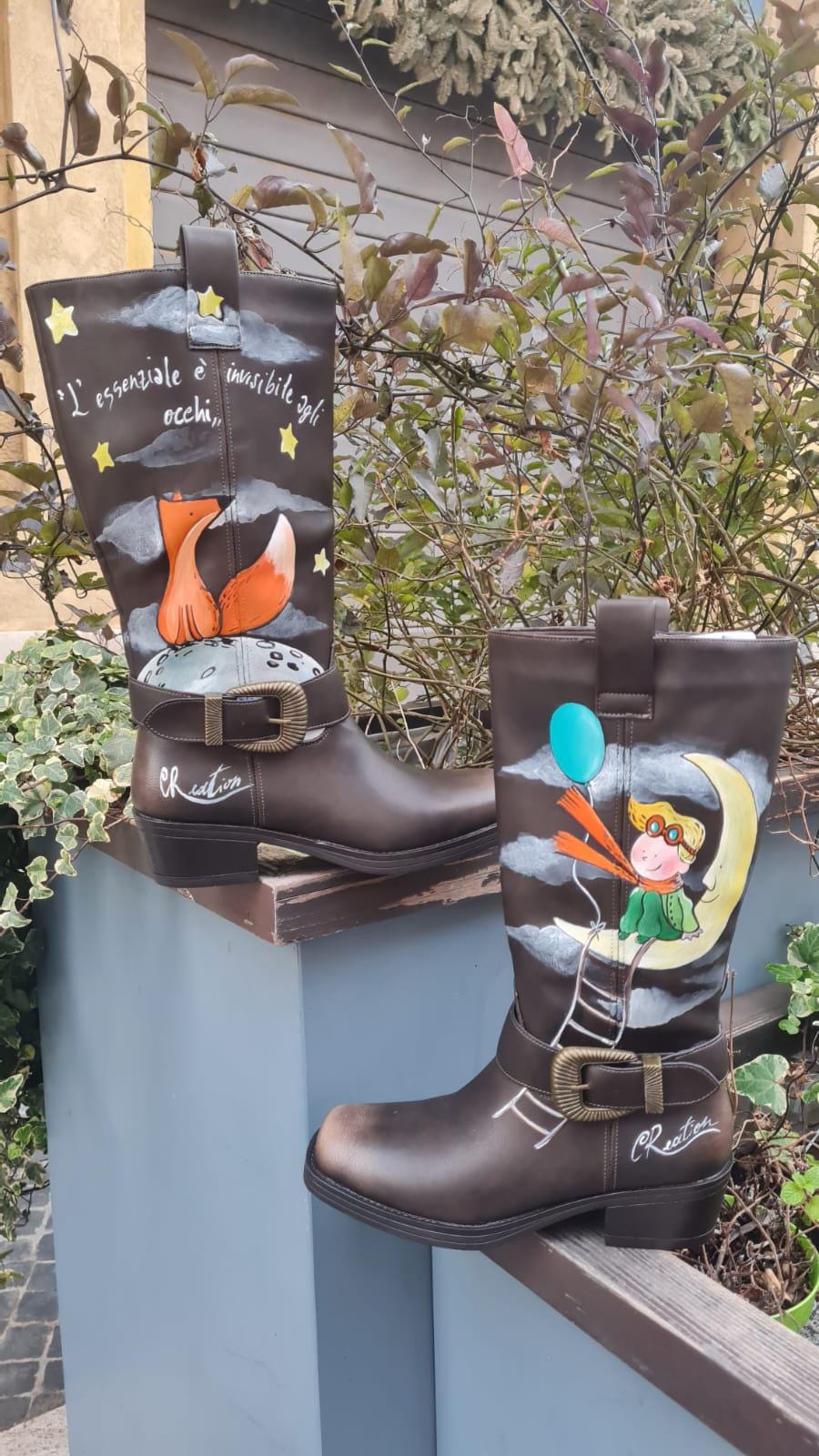 Stivali dipinti a mano - Il Piccolo Principe 🧩 *Coordinabile su richiesta:* È possibile ordinare *un portafoglio , una borsa o un giacchetto perfettamente abbinato* con lo stesso stile e soggetto ! Porta con te la magia del Piccolo Principe con questi stivali unici, dipinti a mano con cura e passione. Il design raffigura il piccolo principe seduto su una luna, mentre la sua fidata amica, la volpe, è disegnata su un pianeta lontano