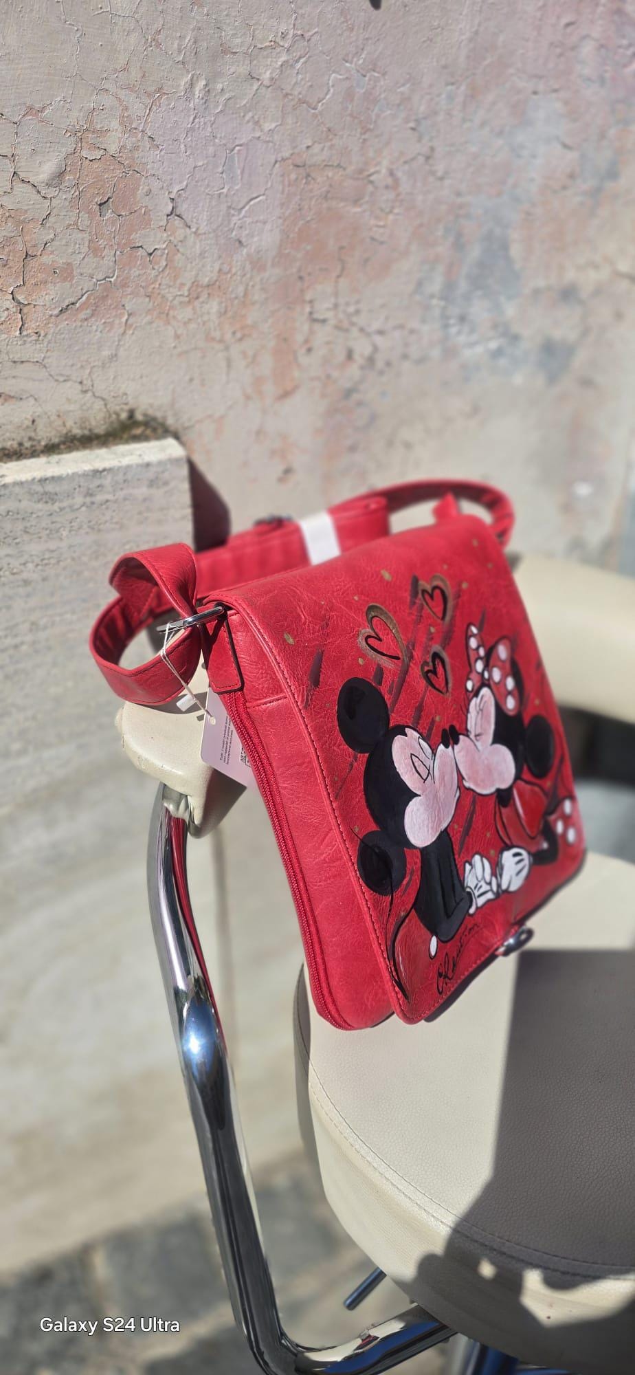 Borsa dipinta a mano – Minnie e Topolino che si baciano – Idea regalo romantica – Personalizzabile *Descrizione* ✨ Borsa unica e romantica, dipinta interamente a mano con il dolcissimo soggetto di Minnie e Topolino che si baciano 💕 Realizzata su base in pelle/ecopelle di alta qualità, resistente e capiente, perfetta per l’uso quotidiano o come idea regalo originale. I colori utilizzati sono acrilici professionali per tessuti, resistenti all’acqua e al tempo