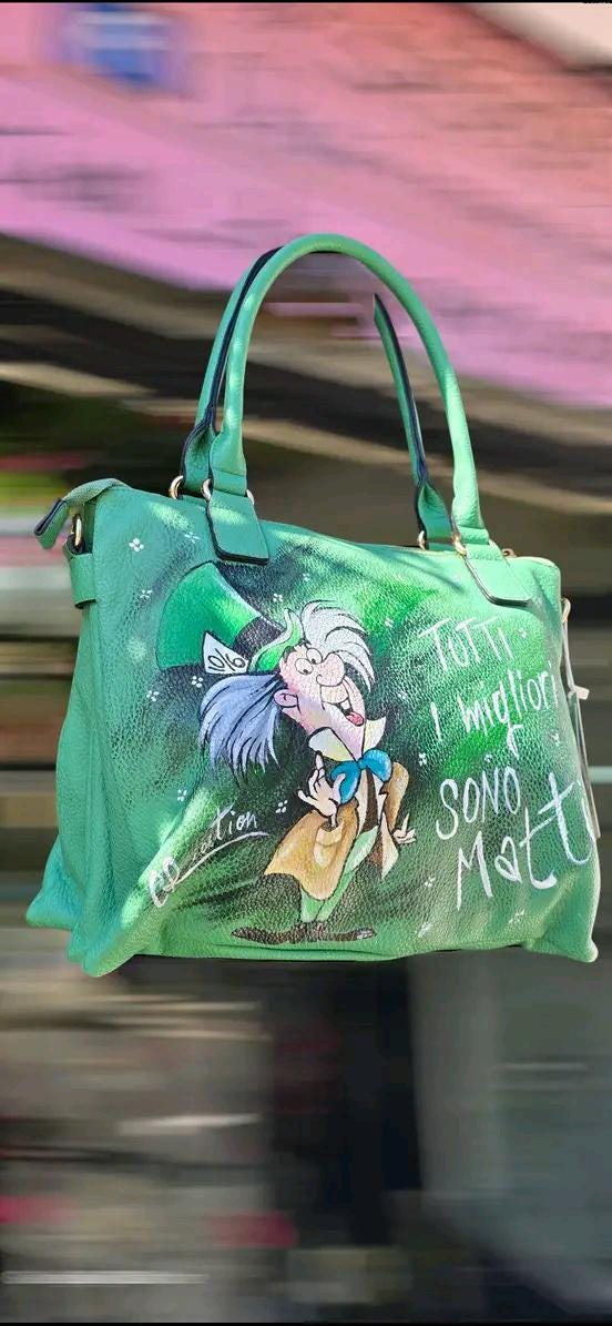 Borsa Dipinta a Mano con Cappellaio Matto - “Tutti i migliori sono matti” - Ecopelle - Personalizzabile 🧩 *Coordinabile su richiesta:* È possibile ordinare *un portafoglio o un giacchetto perfettamente abbinato* con lo stesso stile e soggetto ! Descrizione: Questa borsa dipinta a mano è un omaggio al famoso Cappellaio Matto, personaggio iconico del celebre cartone animato.