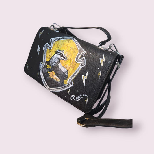 *Borsa Dipinta a Mano – Tassorosso di Harry Potter (Hogwarts) ✨🦡* Questa *borsa artigianale* è un omaggio alla *casa Tassorosso* di *Hogwarts*, simbolo di *lealtà*, *amicizia* e *lavoro di squadra*! 🧙♂️ Dipinta a mano con l’immagine del *Tassorosso*, una delle case più apprezzate e affettuose della scuola di magia, questa borsa è perfetta per tutti i fan di *Harry Potter* che credono nei valori di amicizia e lealtà. Realizzata in *ecopelle* di alta qualità e dipinta con *colori acrilici* resistenti, quest