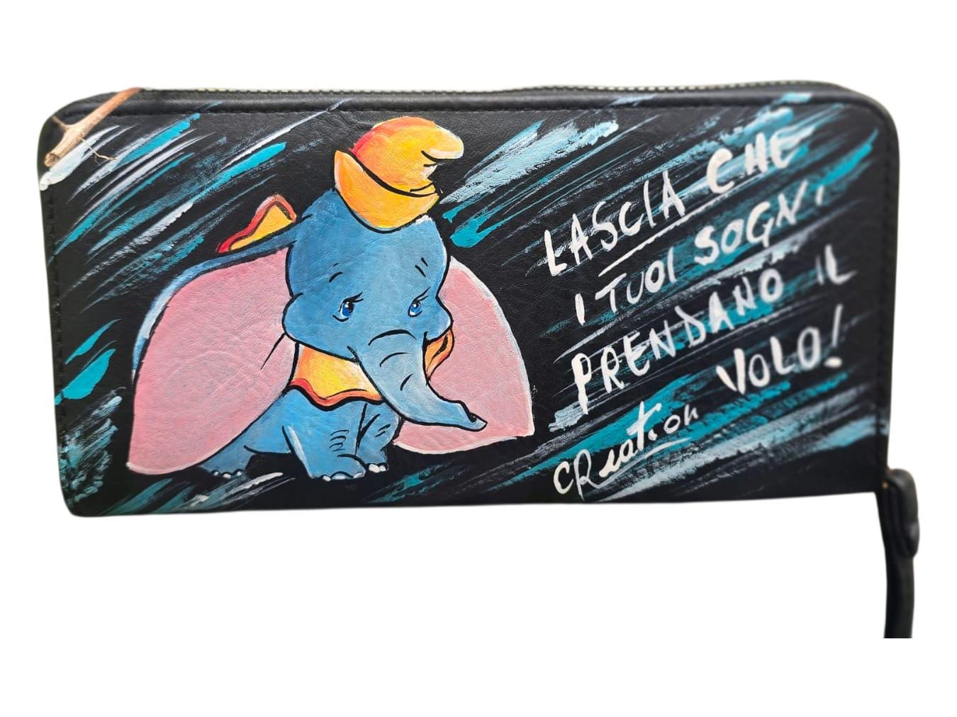 *Portafoglio Dipinto a Mano – Dumbo &amp; Frase Motivazionale 🎨🐘* Un accessorio unico che unisce dolcezza e ispirazione! Questo portafoglio in ecopelle è dipinto a mano con colori acrilici professionali e ha come protagonista *Dumbo*, il tenero elefantino del celebre cartone Disney, accompagnato dalla frase: *"Lascia che i tuoi sogni prendano il volo"* ✨ 🖌️ *Dettagli del prodotto*: - Materiale: Ecopelle - Tecnica: Dipinto a mano con colori acrilici sigillati - Lavabile a mano o in lavatrice fino a 40° - 