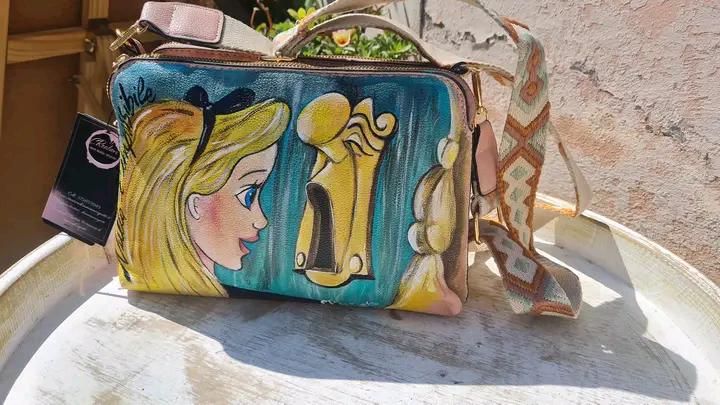 Borsa Dipinta a Mano - Alice nel Paese delle Meraviglie | Accessorio Unico e Magico ✨ Un tocco di fantasia e meraviglia per il tuo stile! ✨ Questa borsa unica è dipinta a mano con colori acrilici resistenti e raffigura Alice nel Paese delle Meraviglie, uno dei personaggi più amati e sognanti della letteratura e del mondo Disney. Un accessorio perfetto per chi ama le fiabe, l’arte e gli oggetti unici fatti a mano.