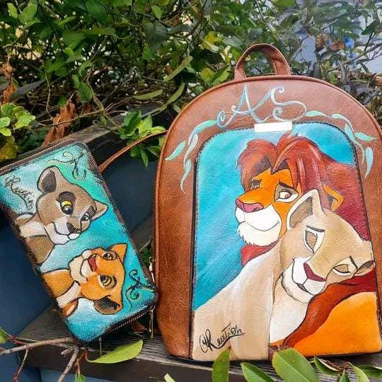 Zaino e Portafoglio Dipinti a Mano - Simba e Nala - Il Re Leone - In Ecopelle - Personalizzabile Porta con te un pezzo del magico mondo de Il Re Leone con questo set unico, composto da zaino e portafoglio dipinti a mano con i protagonisti Simba e Nala. Realizzati con colori acrilici su ecopelle di alta qualità, ogni dettaglio è curato con amore e passione, rendendo questo set perfetto per chi vuole esprimere il proprio amore per il classico Disney in modo originale. 🧩 *Coordinabile su richiesta:* È possibi