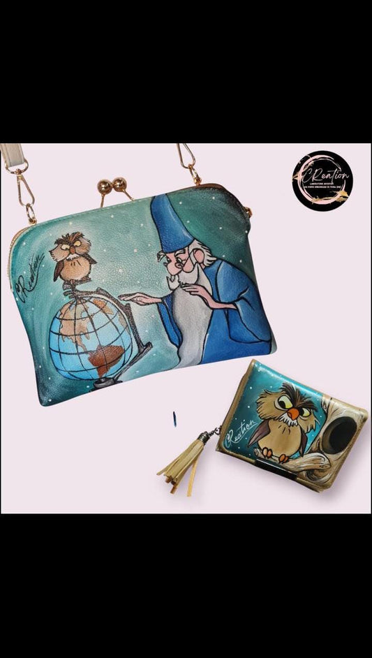 Set Borsa + Portafoglio Dipinti a Mano - Mago Merlino e Gufo Anacleto - Accessori Unici e Artigianali Descrizione: Scopri l'incanto del Mago Merlino e del suo fedele gufo Anacleto con questo set esclusivo di borsa e portafoglio, entrambi dipinti a mano con dettagli magici e affascinanti. Perfetto per gli amanti della magia e delle storie senza tempo, questo set non è solo un accessorio, ma un pezzo d'arte da indossare
