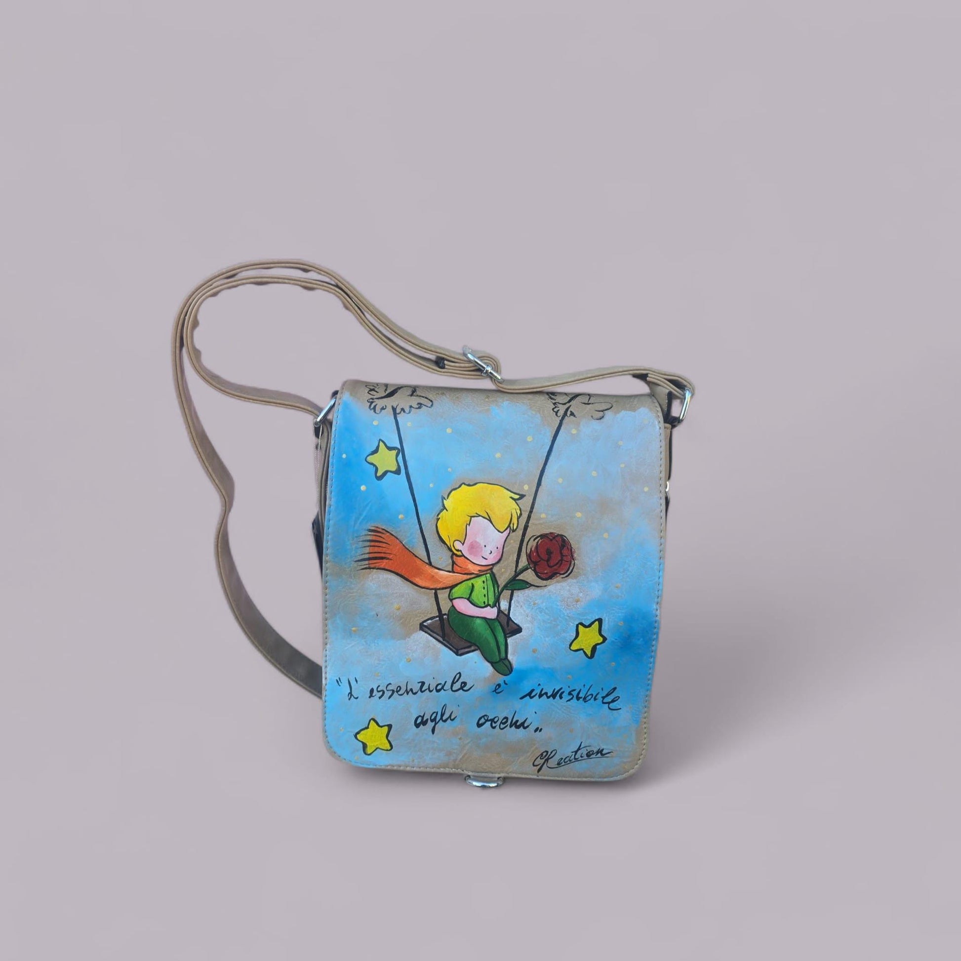 Borsa dipinta a mano – Il Piccolo Principe con frase iconica – Pelle/Ecopelle di alta qualità *Descrizione:* Lasciati ispirare dalla magia senza tempo de *Il Piccolo Principe* con questa borsa capiente, dipinta interamente a mano. Il soggetto principale è l’iconico protagonista del celebre racconto, accompagnato da una frase simbolica che emoziona grandi e piccini. Ogni borsa è realizzata su *pelle o ecopelle di alta qualità*, resistente e piacevole al tatto, e dipinta con *colori acrilici professionali* ad