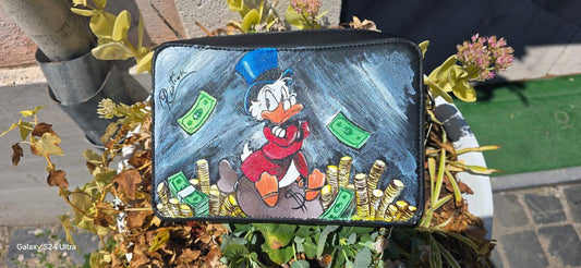 *Borsa Dipinta a Mano – Zio Paperone 💰🦆* Un omaggio al personaggio più iconico e ricco del mondo Disney: *Zio Paperone*! Questa *borsa in ecopelle dipinta a mano* raffigura il celebre papero con il suo immancabile cilindro e le monete d'oro, simbolo di ingegno e determinazione. Ogni dettaglio è realizzato a mano con cura artigianale e *colori acrilici professionali*, rendendo ogni pezzo unico.