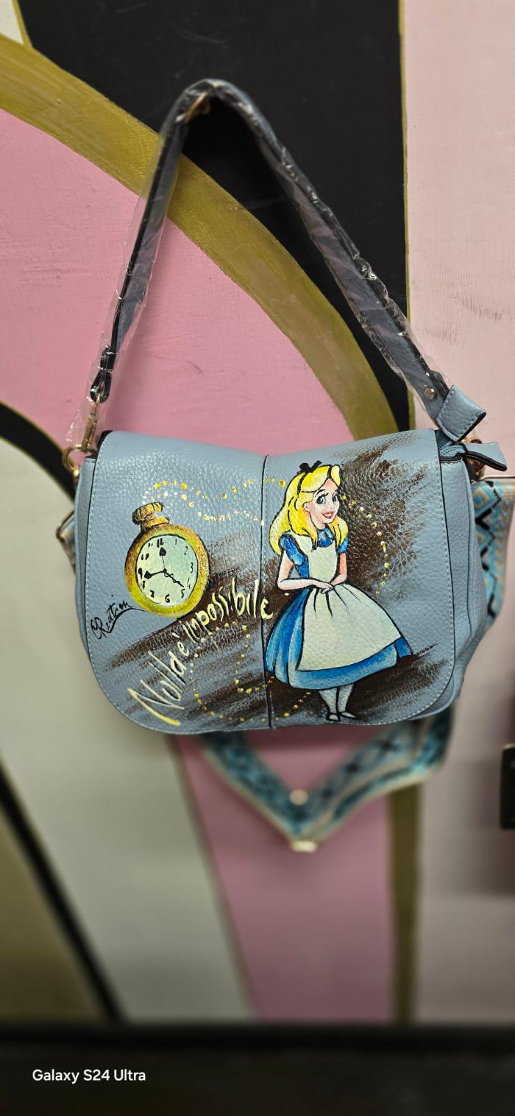 Borsa dipinta a mano "Alice nel Paese delle Meraviglie" - Scritta "Nulla è impossibile" Questa borsa in ecopelle è un'opera unica, realizzata interamente a mano con colori acrilici di alta qualità. Il design rappresenta un omaggio al classico "Alice nel Paese delle Meraviglie", con l'aggiunta della frase "Nulla è impossibile", che conferisce un tocco di magia e ispirazione a ogni outfit. 🧩 *Coordinabile su richiesta:*