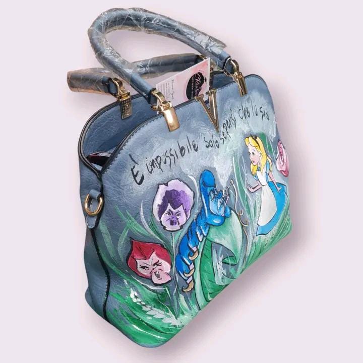 Borsa Dipinta a Mano - Alice e Brucaliffo - In Ecopelle - Colori Acrilici - Unica e Personalizzata 🧩 *Coordinabile su richiesta:* È possibile ordinare *un portafoglio o un giacchetto perfettamente abbinato* con lo stesso stile e soggetto ! Questa borsa dipinta a mano è ispirata al magico mondo di Alice nel Paese delle Meraviglie e presenta i protagonisti Alice e il Brucaliffo