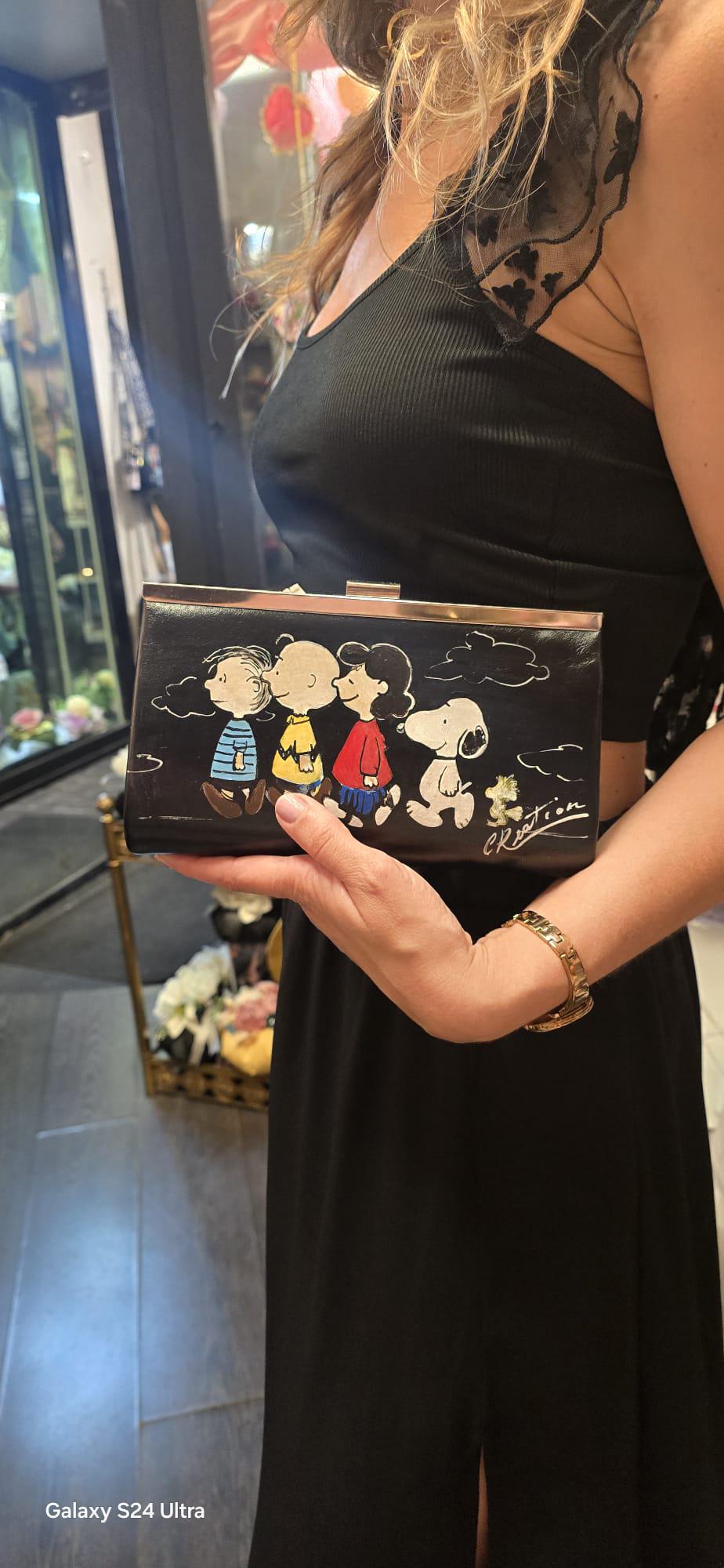 *Borsa Dipinta a Mano – Snoopy &amp; Friends 🐾🎨* Colorata, divertente e dal tocco unico! Questa *borsa in ecopelle* è dipinta interamente a mano e ha come soggetto principale *Snoopy* insieme agli altri personaggi iconici del mondo dei Peanuts. Perfetta per chi ama lo stile originale e vuole portare sempre con sé un tocco di tenerezza e allegria! 👜 *Dettagli del prodotto:* - Materiale: Ecopelle