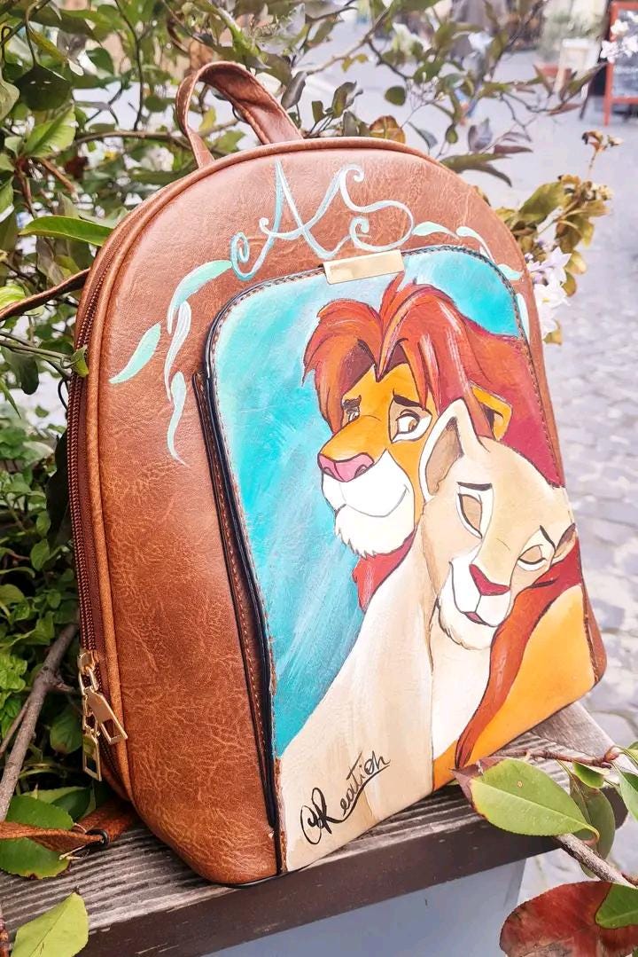 Zaino e Portafoglio Dipinti a Mano - Simba e Nala - Il Re Leone - In Ecopelle - Personalizzabile Porta con te un pezzo del magico mondo de Il Re Leone con questo set unico, composto da zaino e portafoglio dipinti a mano con i protagonisti Simba e Nala. Realizzati con colori acrilici su ecopelle di alta qualità, ogni dettaglio è curato con amore e passione, rendendo questo set perfetto per chi vuole esprimere il proprio amore per il classico Disney in modo originale. 🧩 *Coordinabile su richiesta:* È possibi
