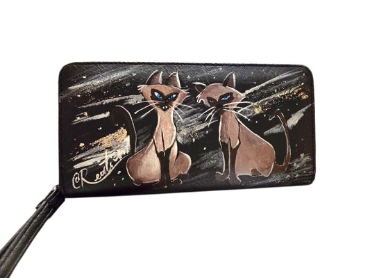 Portafoglio dipinto a mano – Gatti Siamesi dal cartone *Lilli e il Vagabondo* *Descrizione:* Portafoglio artigianale dipinto a mano con i celebri e simpatici gatti siamesi del classico Disney *Lilli e il Vagabondo*. Un pezzo unico, realizzato con cura e attenzione ai dettagli, ideale per chi ama distinguersi con accessori originali e personalizzati. Perfetto anche come idea regalo per gli amanti del mondo