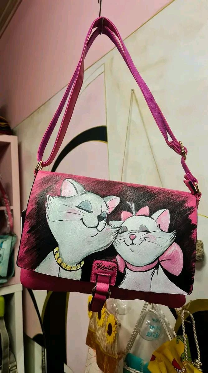 Borsa Dipinta a Mano con Personaggi degli Aristogatti - Borsa Unica in Ecopelle, Personalizzabile, Regalo Originale Descrizione: Questa borsa dipinta a mano è ispirata ai celebri personaggi del cartone animato Gli Aristogatti. Realizzata in ecopelle di alta qualità, la borsa presenta un'illustrazione unica che raffigura i simpatici gatti protagonisti. La pittura è realizzata con colori acrilici, che garantiscono una lunga durata e un aspetto vibrante