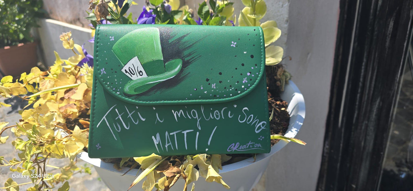 *Borsa Dipinta a Mano – Cappellaio Matto 🎩✨* Un pezzo unico e originale per chi ama il mondo incantato di Alice nel Paese delle Meraviglie! Questa borsa in ecopelle è interamente *dipinta a mano* con colori acrilici professionali e sigillata per durare nel tempo. Il *soggetto principale* è l’iconico *cappello del Cappellaio Matto*, accompagnato dalla celebre frase: *“Tutti i migliori sono matti”*