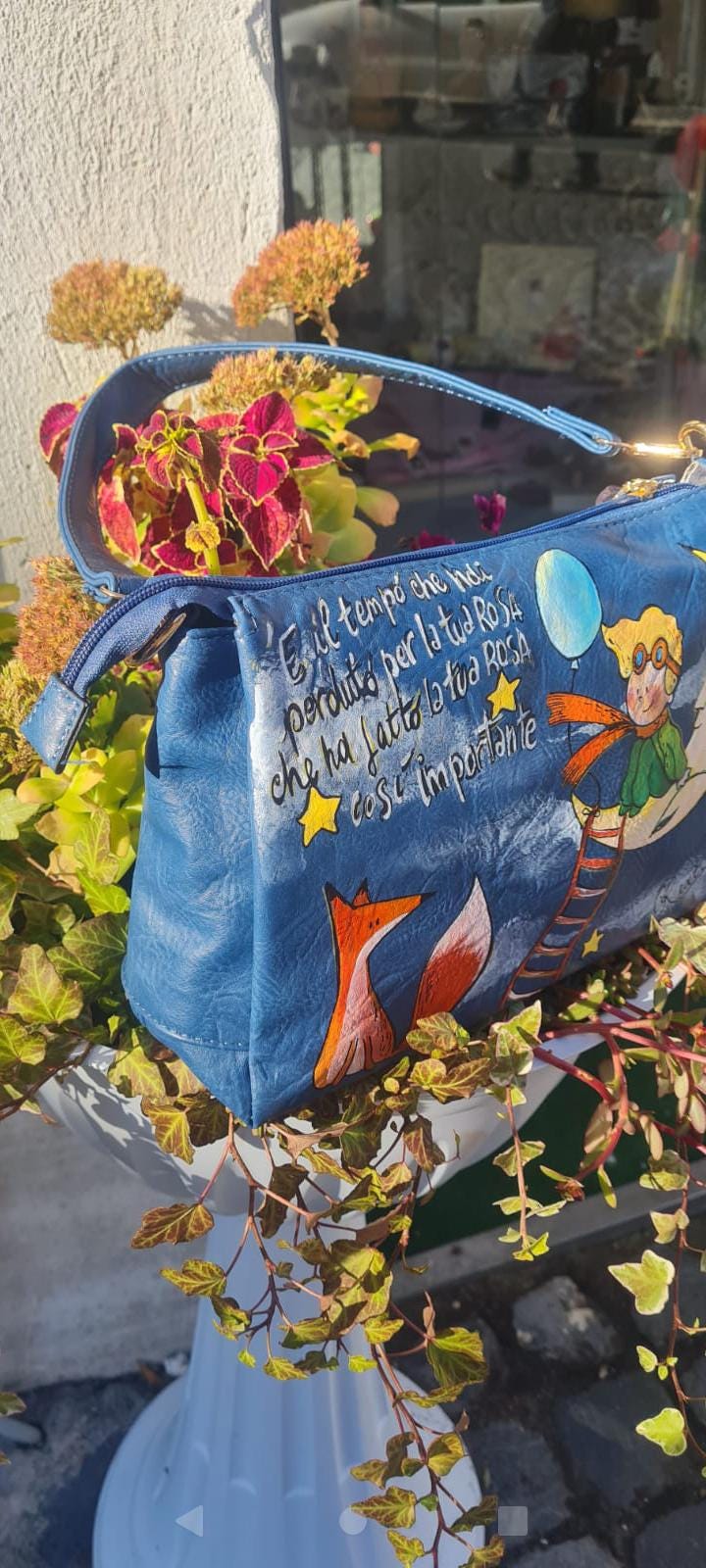 Borsa Dipinta a Mano - Il Piccolo Principe | Accessorio Unico e Magico Porta con te un pezzo di magia e saggezza con questa borsa dipinta a mano, che celebra il Piccolo Principe, il celebre personaggio creato da Antoine de Saint-Exupéry. Ogni borsa è realizzata con amore, utilizzando colori acrilici di alta qualità, per un design unico che racconta una storia di avventura, sogni e riflessioni. 🧩 *Coordinabile su richiesta:* È possibile ordinare *un portafoglio o un giacchetto perfettamente abbinato* con lo
