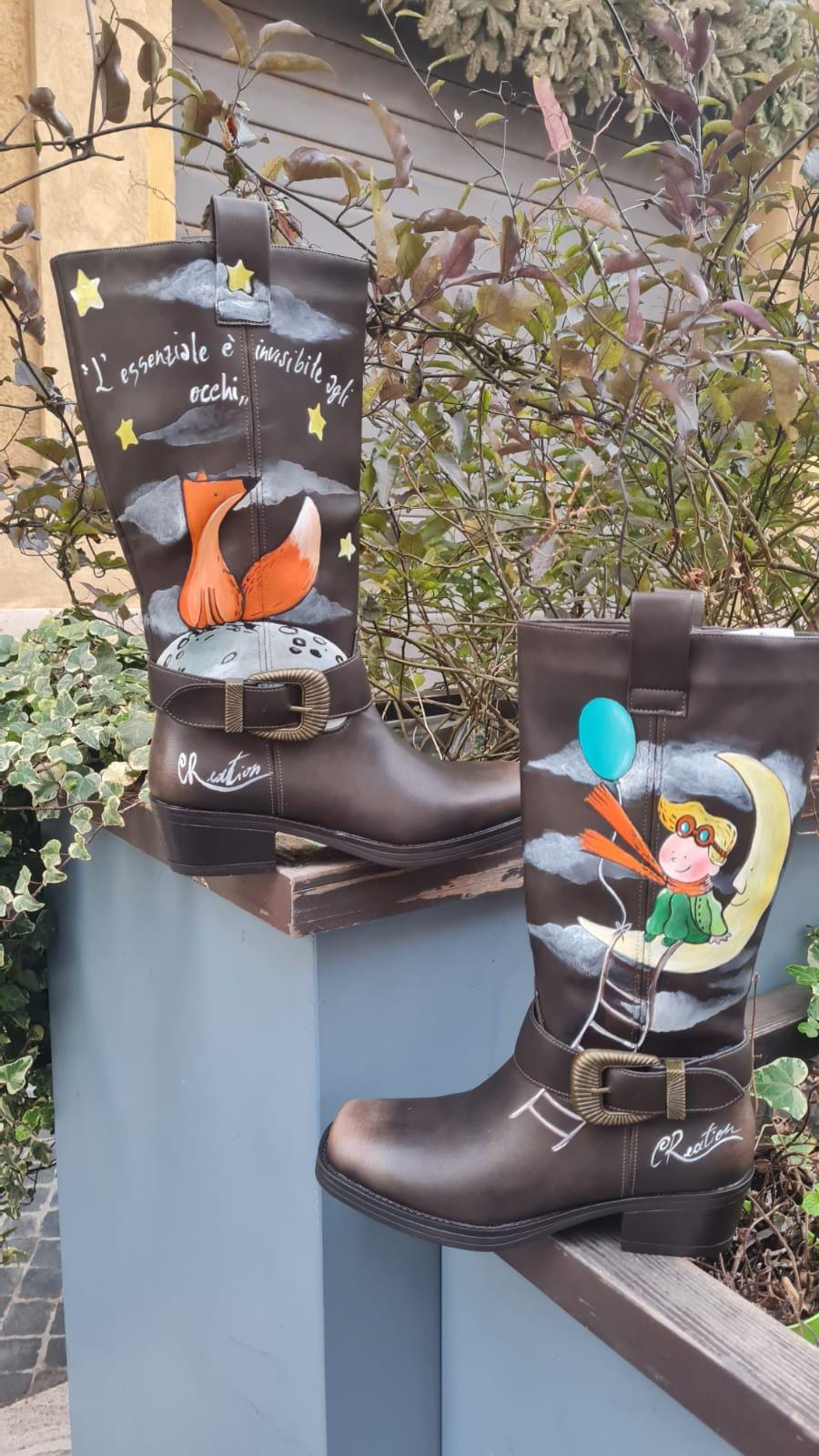 Stivali dipinti a mano - Il Piccolo Principe 🧩 *Coordinabile su richiesta:* È possibile ordinare *un portafoglio , una borsa o un giacchetto perfettamente abbinato* con lo stesso stile e soggetto ! Porta con te la magia del Piccolo Principe con questi stivali unici, dipinti a mano con cura e passione. Il design raffigura il piccolo principe seduto su una luna, mentre la sua fidata amica, la volpe, è disegnata su un pianeta lontano