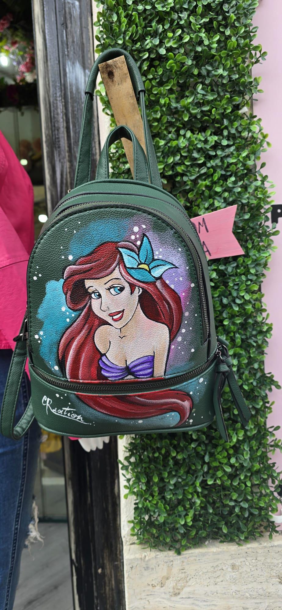 Zainetto Dipinto a Mano – Ariel La Sirenetta – Zaino Unico e Personalizzato *Descrizione:* 🎨 Zainetto artigianale dipinto interamente a mano, ispirato alla magia della Sirenetta! Il soggetto principale è Ariel, con colori intensi, dettagli curati e uno stile fiabesco perfetto per chi ama il mare e le storie incantate. 👜 *Caratteristiche:* • Realizzato in pelle/ecopelle di alta qualità • Dipinto a mano con colori acrilici professionali, resistenti e durevoli • Spazioso, comodo, con tasche interne e chiusur