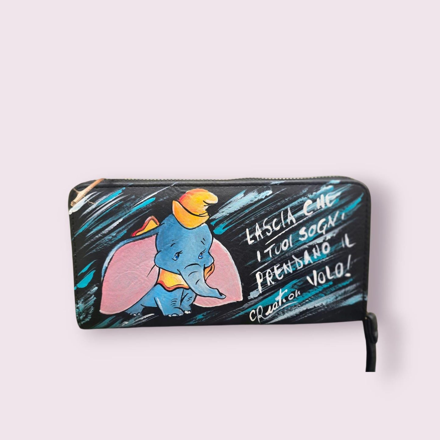 *Portafoglio Dipinto a Mano – Dumbo &amp; Frase Motivazionale 🎨🐘* Un accessorio unico che unisce dolcezza e ispirazione! Questo portafoglio in ecopelle è dipinto a mano con colori acrilici professionali e ha come protagonista *Dumbo*, il tenero elefantino del celebre cartone Disney, accompagnato dalla frase: *"Lascia che i tuoi sogni prendano il volo"* ✨ 🖌️ *Dettagli del prodotto*: - Materiale: Ecopelle - Tecnica: Dipinto a mano con colori acrilici sigillati - Lavabile a mano o in lavatrice fino a 40° - 