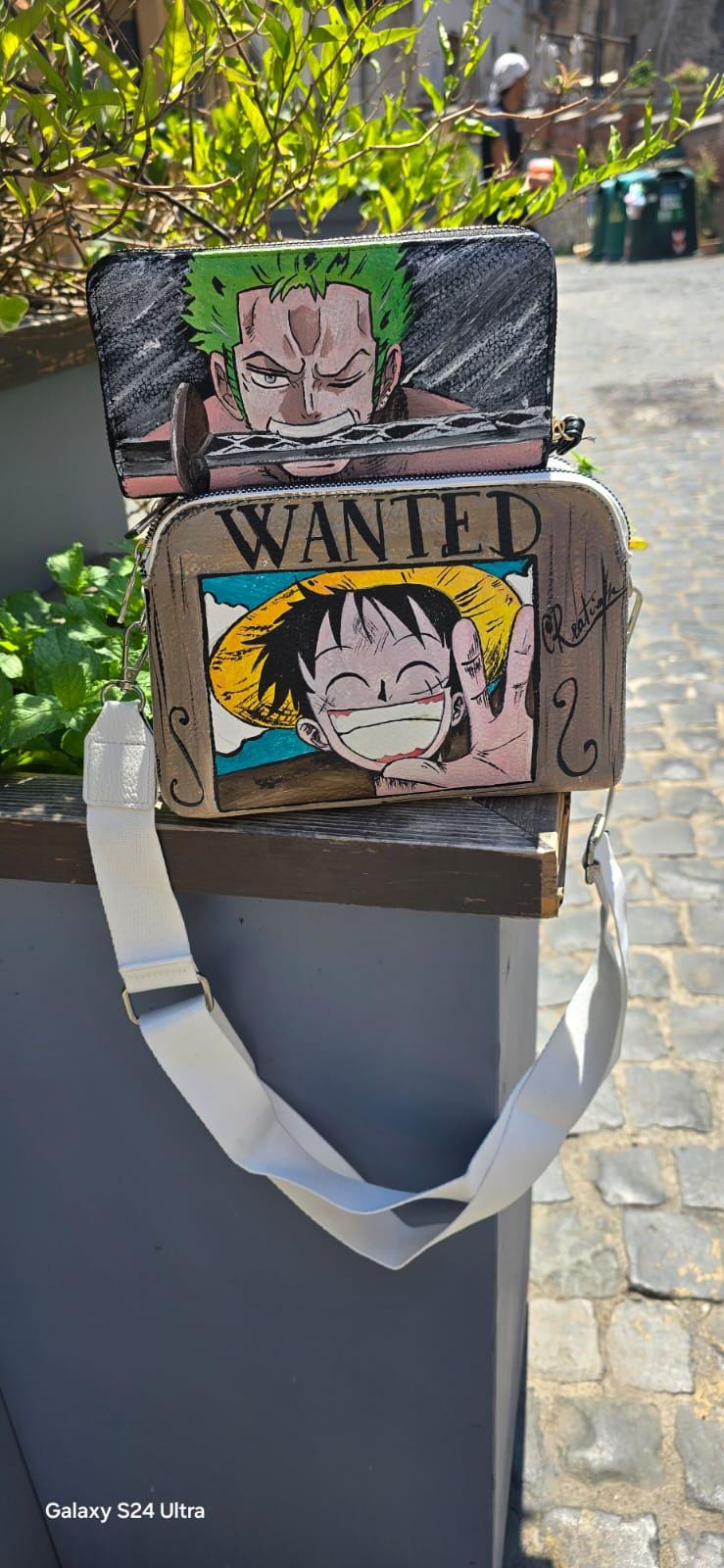 *Borsa Dipinta a Mano – Rubber Cappello di Paglia (One Piece) 🏴☠️🎨* Un accessorio unico per veri fan di One Piece! Questa *borsa in ecopelle dipinta a mano* ha come soggetto principale *Rubber (Luffy)* con il suo iconico *cappello di paglia*, simbolo di libertà e avventura. Realizzata con *colori acrilici professionali*, ogni borsa è un pezzo artigianale unico, perfett