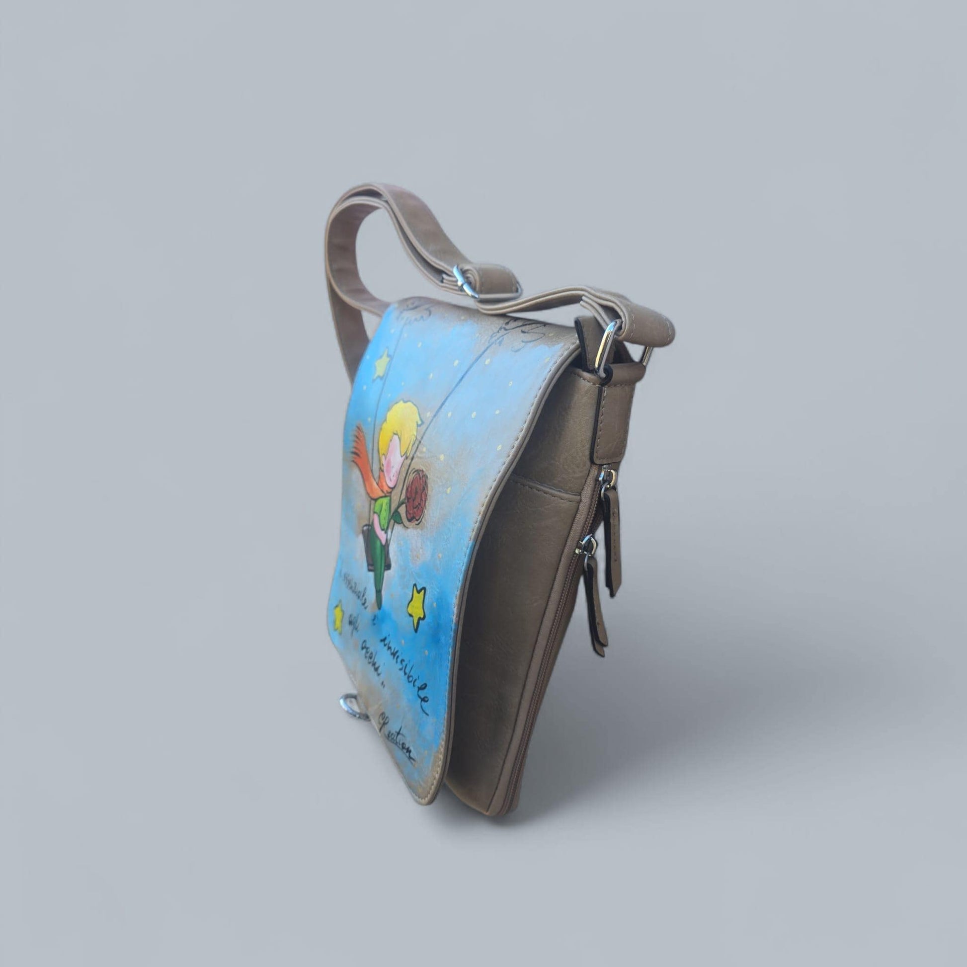 Borsa dipinta a mano – Il Piccolo Principe con frase iconica – Pelle/Ecopelle di alta qualità *Descrizione:* Lasciati ispirare dalla magia senza tempo de *Il Piccolo Principe* con questa borsa capiente, dipinta interamente a mano. Il soggetto principale è l’iconico protagonista del celebre racconto, accompagnato da una frase simbolica che emoziona grandi e piccini. Ogni borsa è realizzata su *pelle o ecopelle di alta qualità*, resistente e piacevole al tatto, e dipinta con *colori acrilici professionali* ad