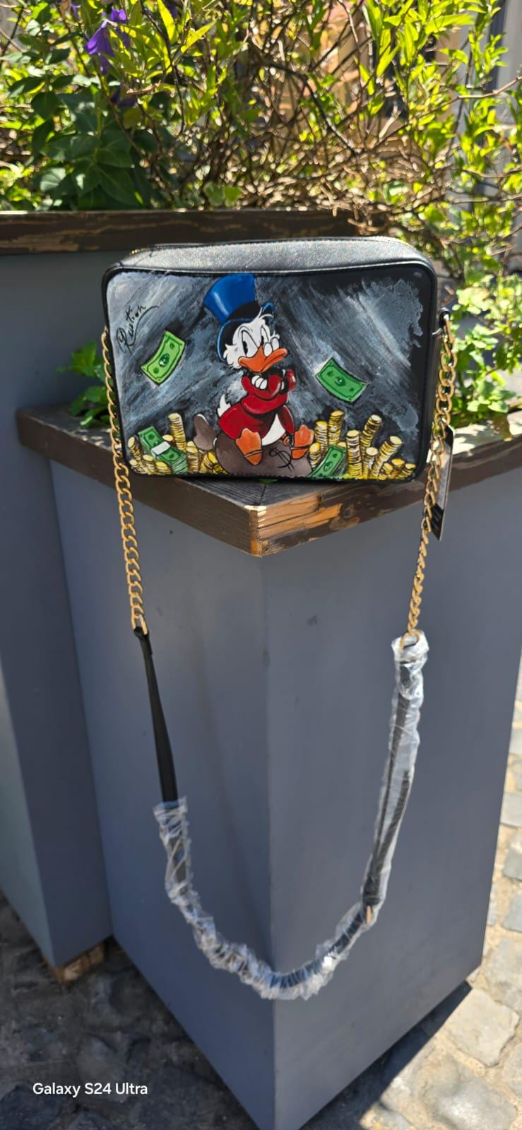 *Borsa Dipinta a Mano – Zio Paperone 💰🦆* Un omaggio al personaggio più iconico e ricco del mondo Disney: *Zio Paperone*! Questa *borsa in ecopelle dipinta a mano* raffigura il celebre papero con il suo immancabile cilindro e le monete d'oro, simbolo di ingegno e determinazione. Ogni dettaglio è realizzato a mano con cura artigianale e *colori acrilici professionali*, rendendo ogni pezzo unico.