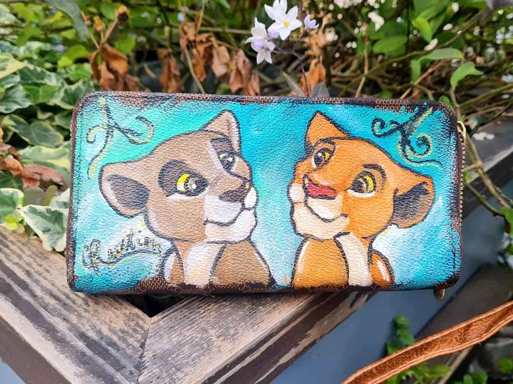 Zaino e Portafoglio Dipinti a Mano - Simba e Nala - Il Re Leone - In Ecopelle - Personalizzabile Porta con te un pezzo del magico mondo de Il Re Leone con questo set unico, composto da zaino e portafoglio dipinti a mano con i protagonisti Simba e Nala. Realizzati con colori acrilici su ecopelle di alta qualità, ogni dettaglio è curato con amore e passione, rendendo questo set perfetto per chi vuole esprimere il proprio amore per il classico Disney in modo originale. 🧩 *Coordinabile su richiesta:* È possibi