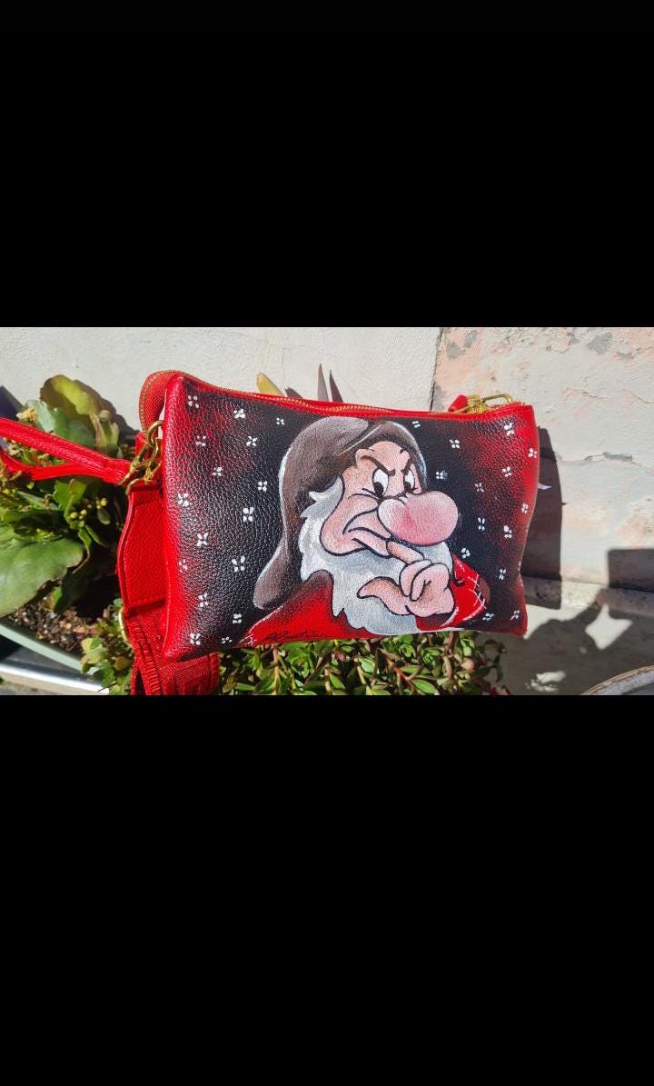 Borsa a Tracolla con Zip Dipinta a Mano - Brontolo | Biancaneve e i Sette Nani | Accessorio Unico e Originale 🧩 *Coordinabile su richiesta:* È possibile ordinare *un portafoglio o un giacchetto perfettamente abbinato* con lo stesso stile e soggetto ! Aggiungi un tocco di magia e personalità al tuo stile con questa borsa a tracolla dipinta a mano, che raffigura il caratteristico e burbero Brontolo di Biancaneve e i Sette Nani