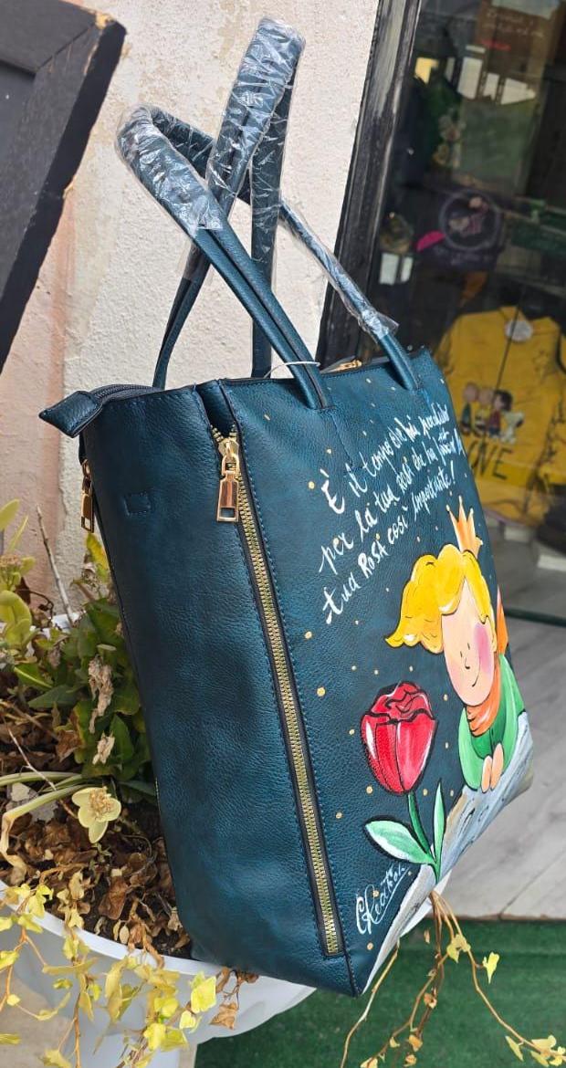 Borsa Grande in Ecopelle Dipinta a Mano – Ispirazione Il Piccolo Principe con Rosa Rosa e Frase Iconica ✨🌹 Descrizione : 🎨 Borsa artigianale grande in ecopelle/pelle, dipinta interamente a mano con amore e cura. Il soggetto principale è ispirato al poetico mondo de Il Piccolo Principe, rappresentato con una delicata rosa rosa 🌹 e una frase iconica che rende il pezzo ancora più speciale 💫. 👜 Capiente, comoda e originale