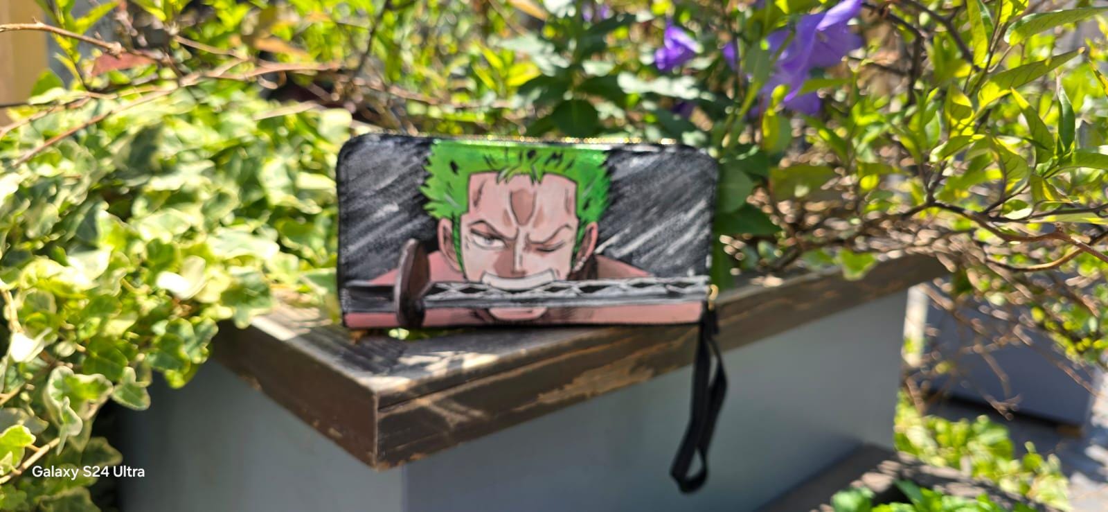 *Portafoglio Dipinto a Mano – Zoro (One Piece) 🏴☠️🎨* Porta con te lo stile dei pirati! Questo *portafoglio in ecopelle dipinto a mano* ha come soggetto principale *Zoro*, uno dei personaggi più amati del celebre anime *One Piece*. Realizzato con *colori acrilici professionali* e sigillato per garantire resistenza nel tempo, è perfetto per fan e collezionisti!