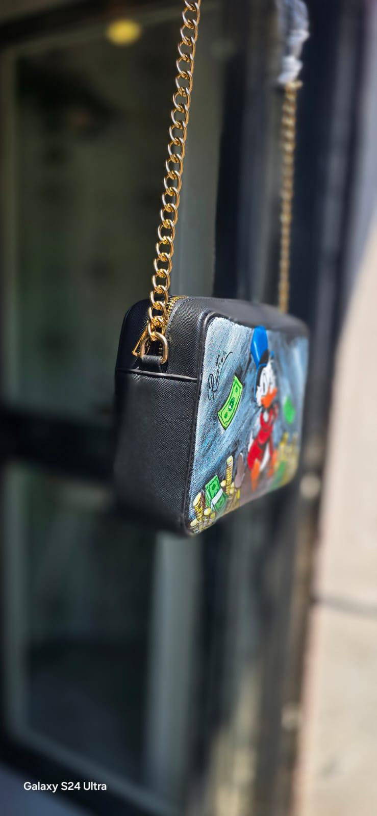 *Borsa Dipinta a Mano – Zio Paperone 💰🦆* Un omaggio al personaggio più iconico e ricco del mondo Disney: *Zio Paperone*! Questa *borsa in ecopelle dipinta a mano* raffigura il celebre papero con il suo immancabile cilindro e le monete d'oro, simbolo di ingegno e determinazione. Ogni dettaglio è realizzato a mano con cura artigianale e *colori acrilici professionali*, rendendo ogni pezzo unico.