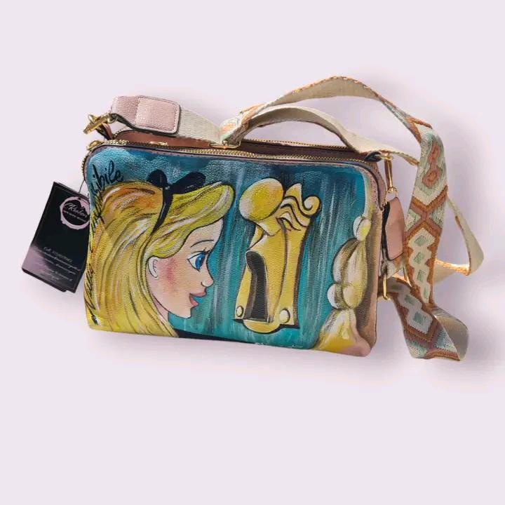 Borsa Dipinta a Mano - Alice nel Paese delle Meraviglie | Accessorio Unico e Magico ✨ Un tocco di fantasia e meraviglia per il tuo stile! ✨ Questa borsa unica è dipinta a mano con colori acrilici resistenti e raffigura Alice nel Paese delle Meraviglie, uno dei personaggi più amati e sognanti della letteratura e del mondo Disney. Un accessorio perfetto per chi ama le fiabe, l’arte e gli oggetti unici fatti a mano.