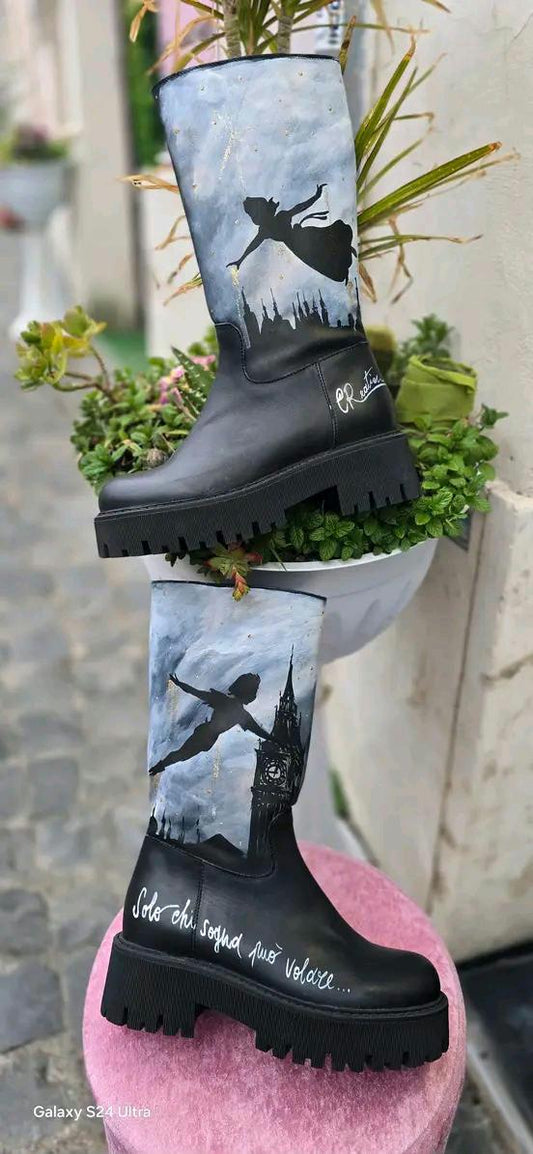 Stivale Dipinto a Mano con Personaggi di Peter Pan - Solo chi sogna può volare 🧩 *Coordinabile su richiesta:* È possibile ordinare *un portafoglio , una borsa o un giacchetto perfettamente abbinato* con lo stesso stile e soggetto ! Aggiungi un tocco di magia al tuo look con questi stivali dipinti a mano, ispirati al mondo incantato di Peter Pan! Ogni paio è realizzato con cura e dettagli, con due personaggi di Peter Pan che volano nel cielo, accompagnati da uno sfondo mozzafiato. La frase "Solo chi sogna p
