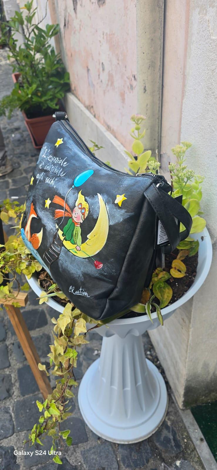 *Borsa dipinta a mano – Il Piccolo Principe e la Volpe* 🌙🦊 Citazione: “L’essenziale è invisibile agli occhi” 🧩 *Coordinabile su richiesta:* È possibile ordinare *un portafoglio o un giacchetto perfettamente abbinato* con lo stesso stile e soggetto ! Borsa in ecopelle nera dipinta interamente a mano con il dolcissimo tema de *Il Piccolo Principe*, protagonista sulla luna con la volpe e una pioggia di stelle. Un pezzo unico e poetico, perfetto per chi ama distinguersi con stile e significato