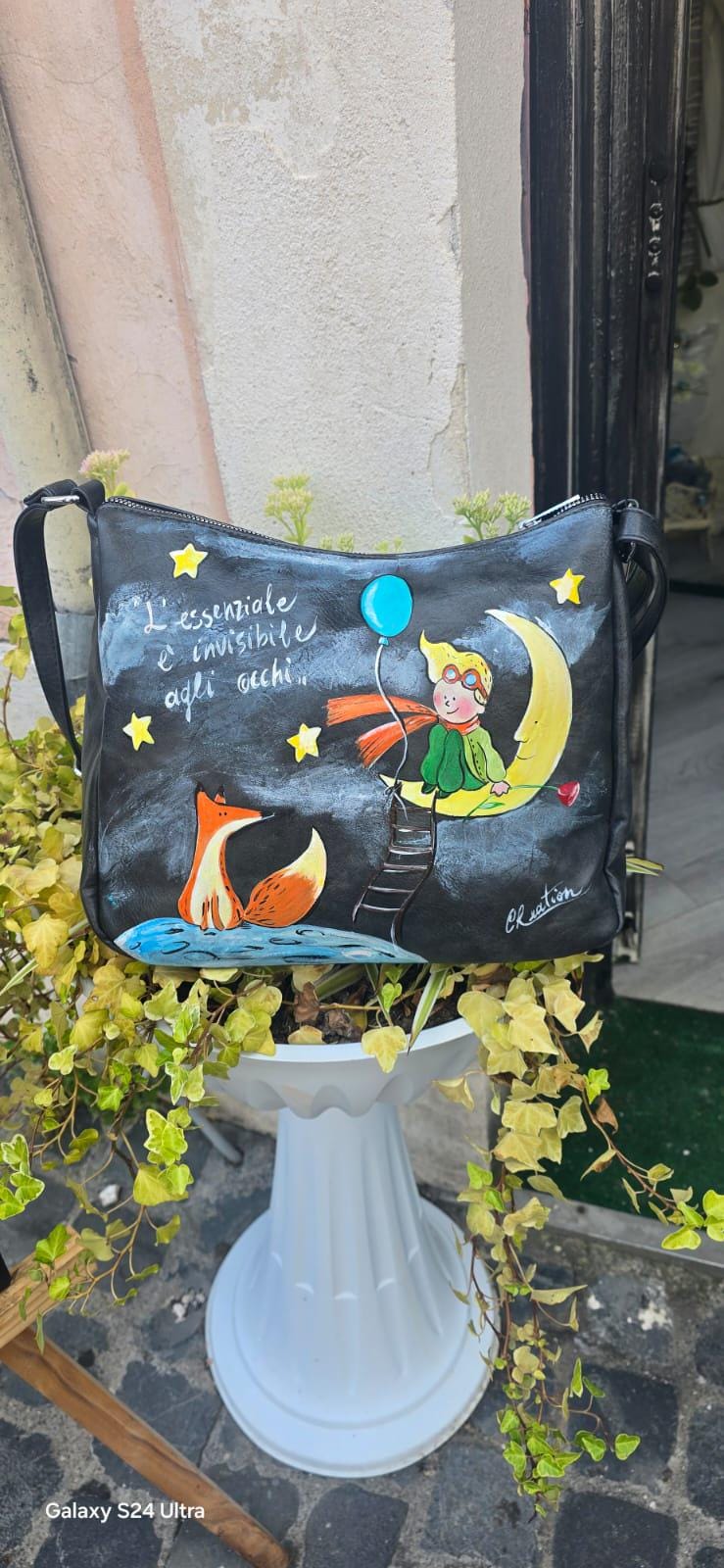 *Borsa dipinta a mano – Il Piccolo Principe e la Volpe* 🌙🦊 Citazione: “L’essenziale è invisibile agli occhi” 🧩 *Coordinabile su richiesta:* È possibile ordinare *un portafoglio o un giacchetto perfettamente abbinato* con lo stesso stile e soggetto ! Borsa in ecopelle nera dipinta interamente a mano con il dolcissimo tema de *Il Piccolo Principe*, protagonista sulla luna con la volpe e una pioggia di stelle. Un pezzo unico e poetico, perfetto per chi ama distinguersi con stile e significato