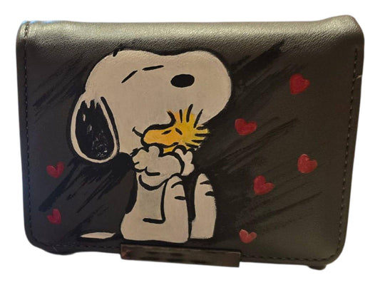 *Portafoglio Dipinto a Mano – Snoopy &amp; Woodstock ❤️🎨* Un portafoglio dolcissimo e originale con protagonista *Snoopy*, il celebre cane dei Peanuts, insieme al suo inseparabile amico *Woodstock*, circondati da cuoricini rossi. Realizzato in ecopelle e *dipinto interamente a mano* con colori acrilici professionali, è perfetto per chi ama distinguersi con stile e tenerezza