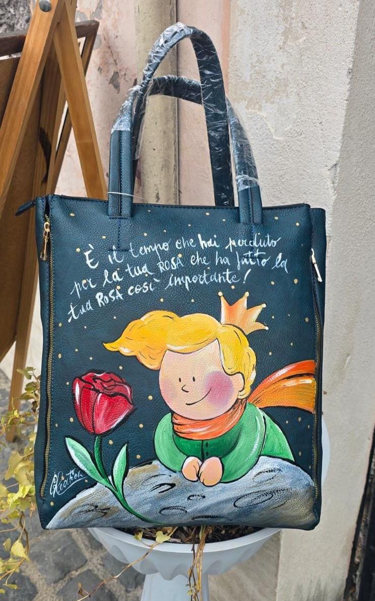 Borsa Grande in Ecopelle Dipinta a Mano – Ispirazione Il Piccolo Principe con Rosa Rosa e Frase Iconica ✨🌹 Descrizione : 🎨 Borsa artigianale grande in ecopelle/pelle, dipinta interamente a mano con amore e cura. Il soggetto principale è ispirato al poetico mondo de Il Piccolo Principe, rappresentato con una delicata rosa rosa 🌹 e una frase iconica che rende il pezzo ancora più speciale 💫. 👜 Capiente, comoda e originale