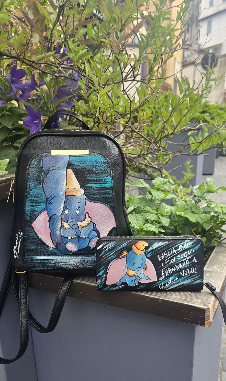 *Portafoglio Dipinto a Mano – Dumbo &amp; Frase Motivazionale 🎨🐘* Un accessorio unico che unisce dolcezza e ispirazione! Questo portafoglio in ecopelle è dipinto a mano con colori acrilici professionali e ha come protagonista *Dumbo*, il tenero elefantino del celebre cartone Disney, accompagnato dalla frase: *"Lascia che i tuoi sogni prendano il volo"* ✨ 🖌️ *Dettagli del prodotto*: - Materiale: Ecopelle - Tecnica: Dipinto a mano con colori acrilici sigillati - Lavabile a mano o in lavatrice fino a 40° - 