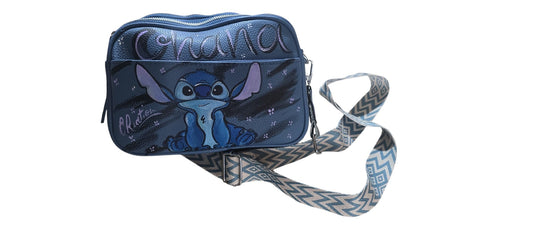Porta con te la vivacità dell'esperimento 626 con questa borsa in ecopelle, dipinta interamente a mano. Il protagonista è il tenero e ribelle Stitch, accompagnato dalla scritta "Ohana", riprodotto con cura nei dettagli per chi ama il mondo Disney, le Hawaii e gli accessori che scaldano il cuore.